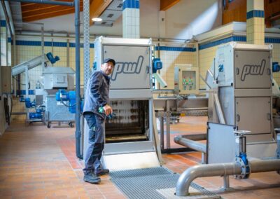 Rechenhalle mit Rechen, Rohrleitungen und Mitarbeiter