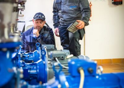 Zwei Mitarbeiter im Pumpenraum mit blauen Pumpenmotoren