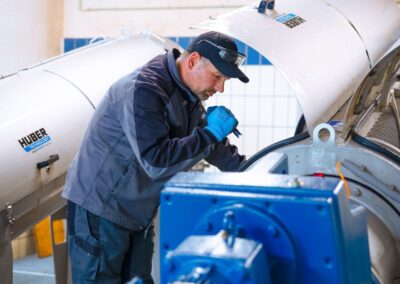 Mitarbeiter an einer Pumpe mit blauem Antrieb im Maschinenraum