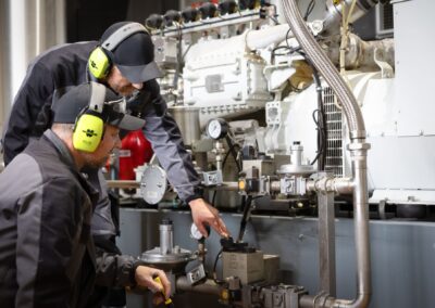 Zwei Mitarbeiter mit Gehörschutz am Biogas-Blockheizkraftwerk