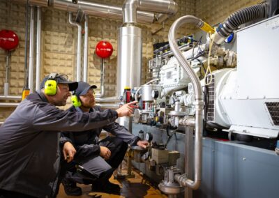 Zwei Mitarbeiter kontrollieren das Biogasaggregat