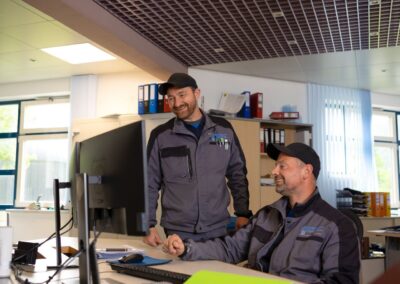 Zwei Mitarbeiter in der Leitwarte am Bildschirmarbeitsplatz