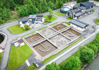 Luftaufnahme mit Nachklärbecken, Belebungsbecken und Betriebsgebäuden neben der Großache