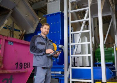 Mitarbeiter mit Tablet neben der Aufbereitungsanlage
