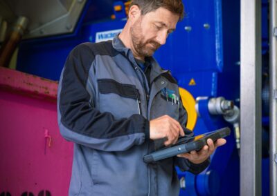 Mitarbeiter mit Tablet an der blauen Aufbereitungsmaschine