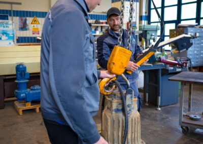 Mitarbeiter hebt eine Pumpe mit dem Hallenkran