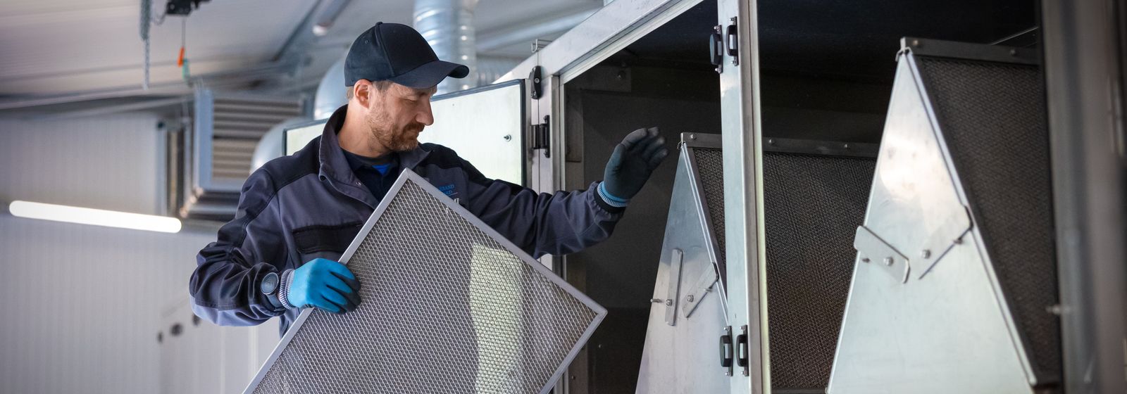 Mitarbeiter wechselt eine Filtermatte am Klärschlammtrockner