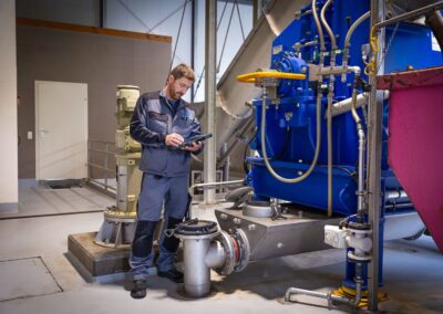 Mitarbeiter mit Tablet an der Bioaufbereitungsanlage für Speisereste